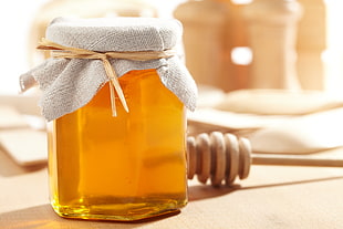 honey filled glass jar near the honey comb